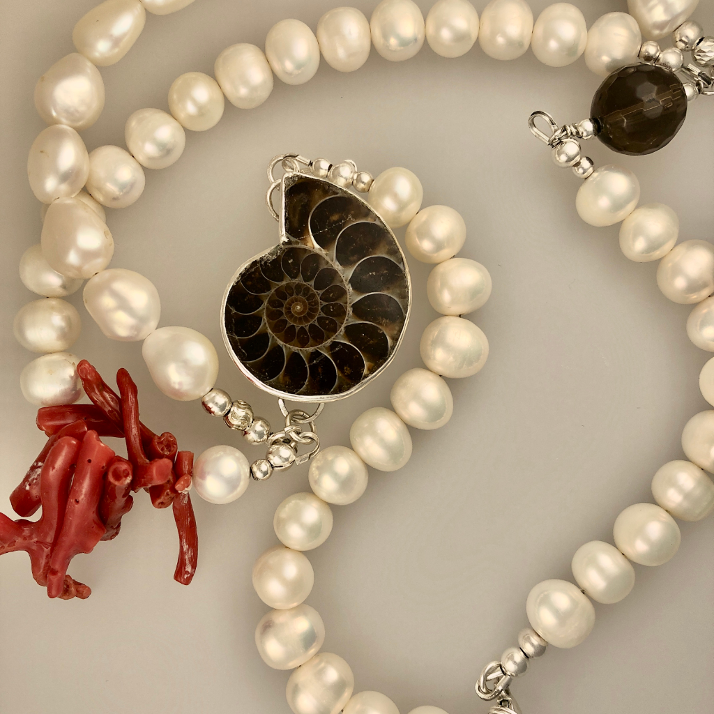 Statement necklace with an Ammonite set in a sterling silver bezel, natural coral and mixed size pearls